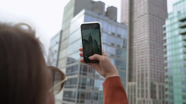 Young woman takes a photo on a mobile phone of skyscrapers in New York.