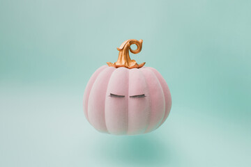 Pink halloween fairy tale pumpkin with golden handle and eyelashes. Green mint background color....