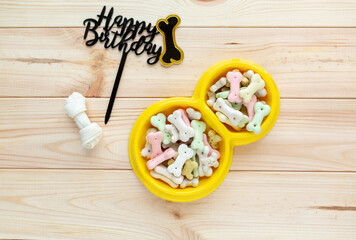 Different multicolored pet care accessories: ring, bones, balls, snacks on natural wooden background. Rubber and textile accessories for dogs. Top view, flat lay. Copy space