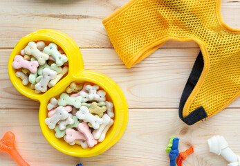 Different multicolored pet care accessories: ring, bones, balls on natural wooden background. Rubber and textile accessories for dogs. Top view, flat lay. Copy space