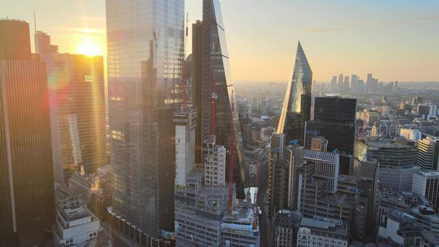 around skyscrapers in City financial and economy centre. View against bright light of rising sun