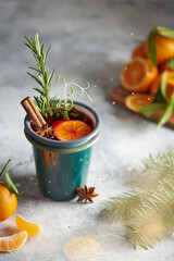 Mulled wine in smalt mug with with fruits and spices. Christmas hot drink on gray stone table. Christmas composition. Christmas concept