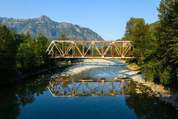 Warren through truss bridge over the North Fork Skykomish River Index WA with Mount Index in the background against a blue sky