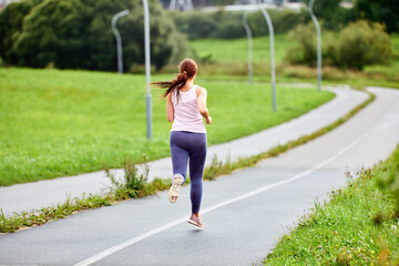 Back view of running woman on road at summer morning.