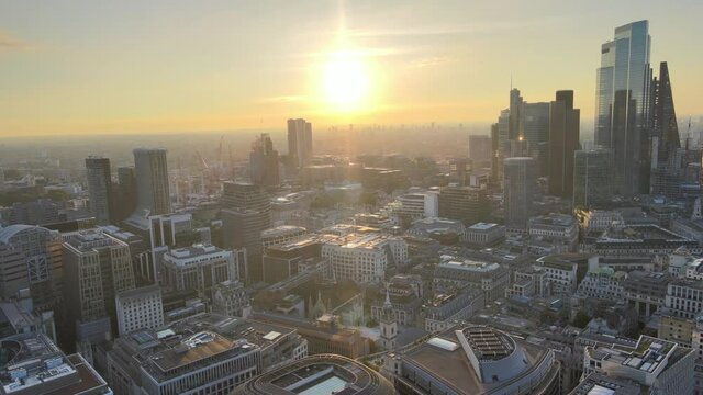 ly above commercial district, Group of tall modern office buildings against sunrise sky