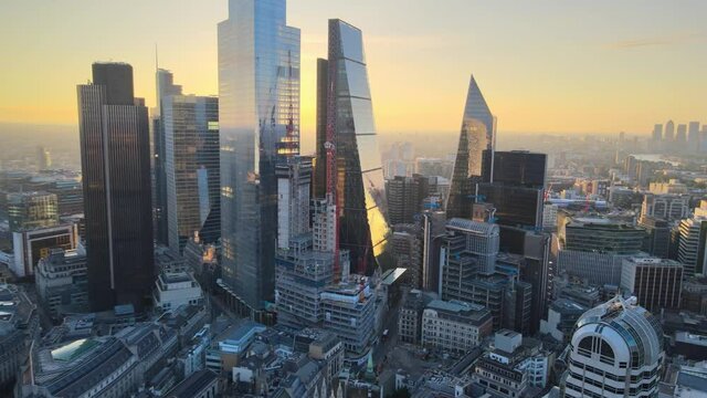 Fly above large town. Modern, luxury and tall skyscrapers with glossy glass facades against rising sun