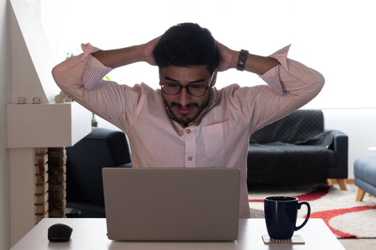 un hombre latino moreno, negro preocupado, estresado mirando laptop - teletrabajo