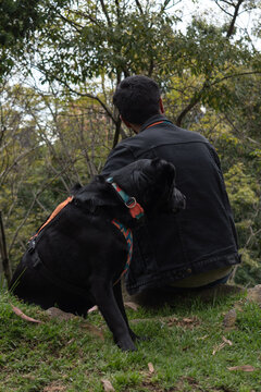 hombre mirando al horizonte junto a su perro negro 