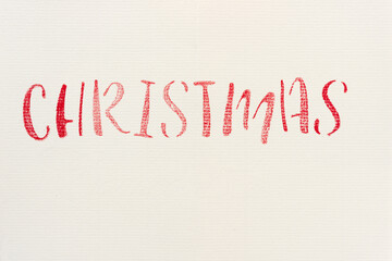 the word "Christmas" stencilled in red on ivory paper