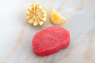 Fresh cut tuna steak with lemon wedges on the kitchen counter