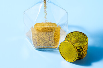 Hourglass and pile of gold coins, time is money, concept: investment, deposit, saving