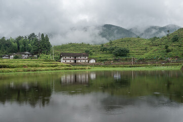 Fototapeta na wymiar The lake reflected the mountain with houses and fog on the mountain