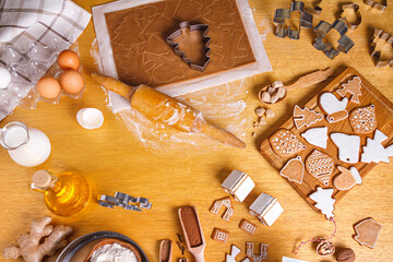 Christmas gingerbread different shaped with sugar icing and ingredients for gingerbread on wooden table, top view, flat lay
