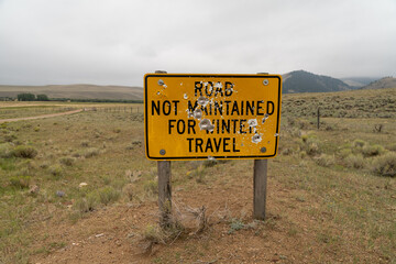 Road not maintained for winter travel sign, with bullet holes
