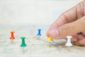 Selective focus of hand holding a pin  on map background