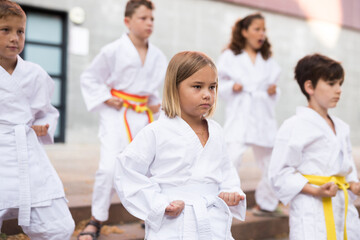 Obraz na płótnie Canvas Group of kids in white kimono training outdoors on street.
