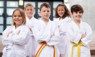 Fototapeta na wymiar Positive children wearing white sports uniform practicing karate on a street near school