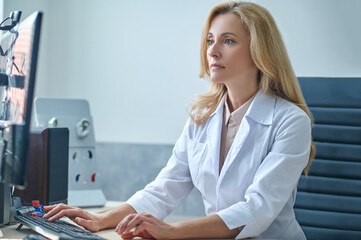 Fototapeta na wymiar Beautiful blonde doctor focused on checking her email