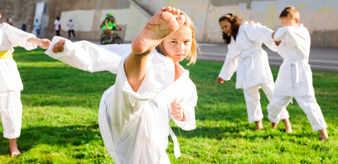 Adorable european preteen girl practicing karate on sunny day in park