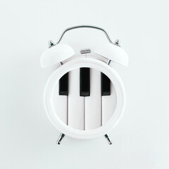 White alarm clock with piano keys isolated on pastel white background. Fun, aesthetic, abstract...