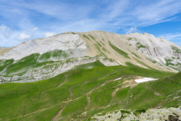 Fototapeta premium Panoramic view of relaxing mountain scenery with mountains in the background and meadow, grass, and rocks on a nice, sunny day