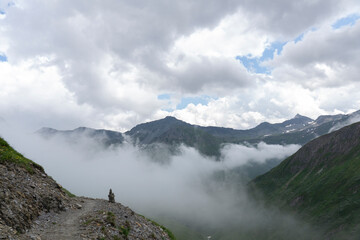 Landscape view of Alps. Peaks cover by clouds and fog because of stormy weather.