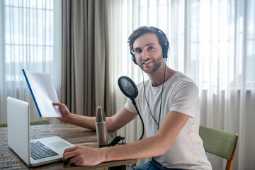 Young bearded man sitting in headphones and having an audio conference