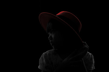 A cute adorable Asian girl wearing red hat about 6years old poses for a photo in the black and white background.