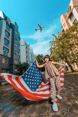 A cute adorable Asian girl about 6years old wearing a vintage dress. An active kid poses for a photo with a large plane flying in the background.