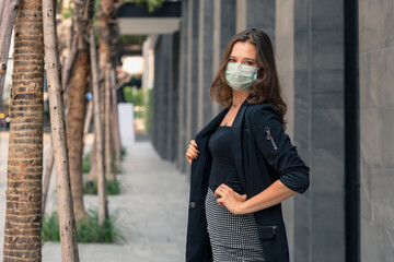 businesswoman wearing face mask posing and looking at camera outdoor