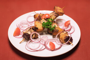 Delicious pork meat and vegetables cut on wooden sticks mix, grilled meat on a white plate
