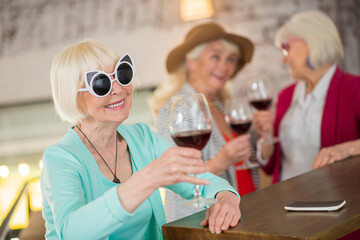 Three senior blonde ladies with glasses of wine in hands