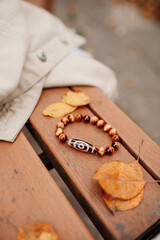 Tibetan talisman bracelet with minerals and magic dzi bead to attract good luck in life. energy trappings. autumn still life bracelet in leaves on wood. selective focus