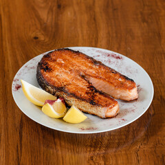 Slice of salmon red fish with lemon, on a white plate 