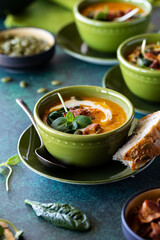 Close up of a bowl of butternut squash soup ready for eating, with other bowls of soup in behind.