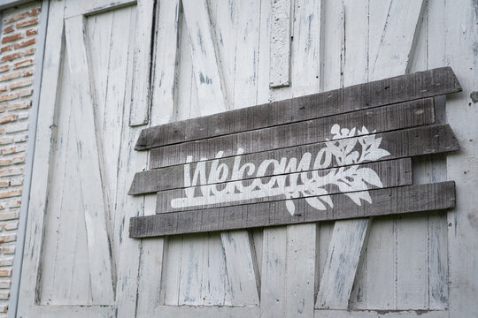 Welcome text sign antique wooden board which is installed on the wall. Sign and symbol object photo in monotone. 