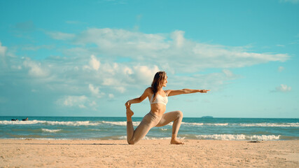 Fototapeta na wymiar Caucasian woman practice yoga on the beach. Young woman practice balance asanas on Summer yoga session on a beach. Happy young woman practicing yoga on the beach at sunset.