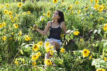 Young girl sitting in a field with sunflowers