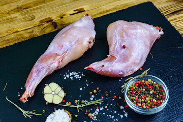 Rabbit meat with pepper, rosemary, salt and garlic on a slate board
