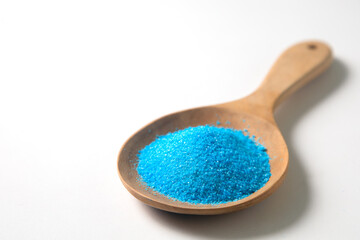 Copper sulfate in wooden spoon on white background.
