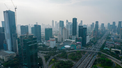 Obraz premium Aerial view of the city traffics at semanggi Roundabout, Jakarta, Indonesia. Aerial view on highways and skyscrapers with noise cloud. Jakarta, Indonesia