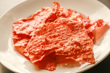 Sliced sheets of dried and crispy pork on white dish.