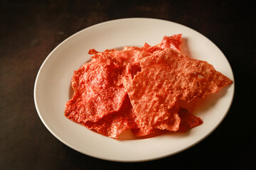 Sliced sheets of dried and crispy pork on white dish.