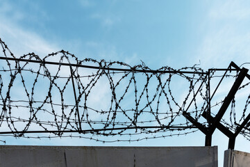 Barbed wire set on a fence against the background of the sky.