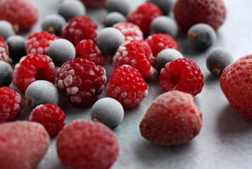 Garden frozen black currant berry, strawberries and red raspberries in white frost, top view, place for tex