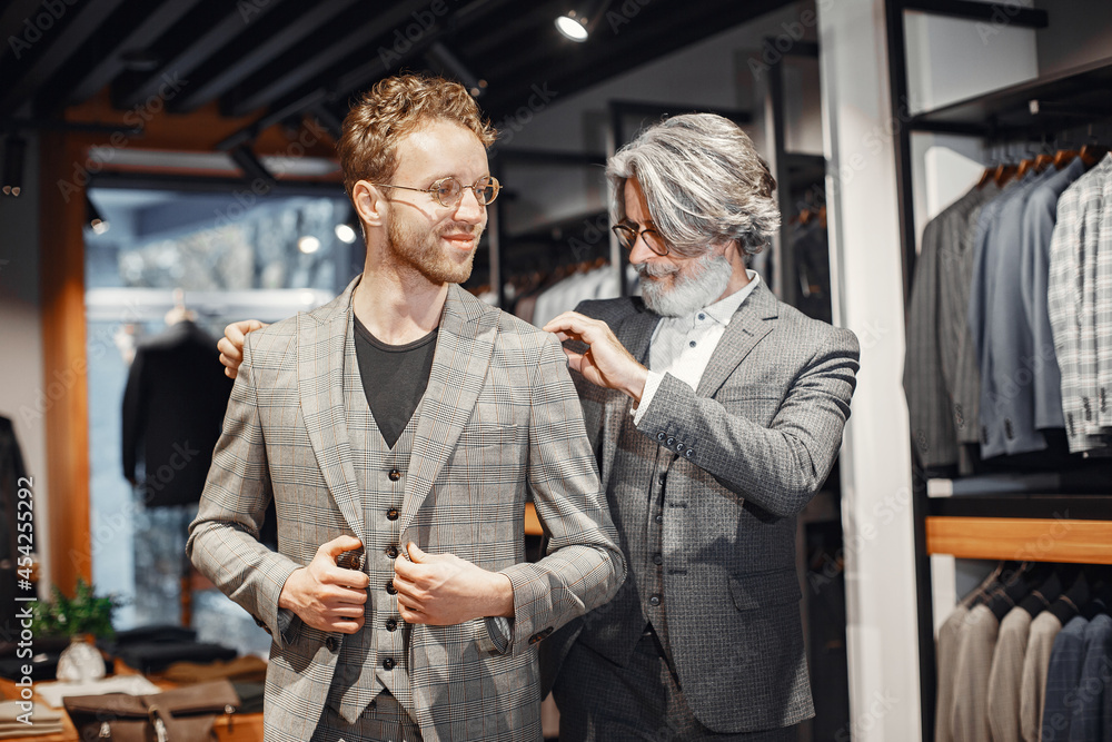 Wall mural Senior man choosing a new suit in a store