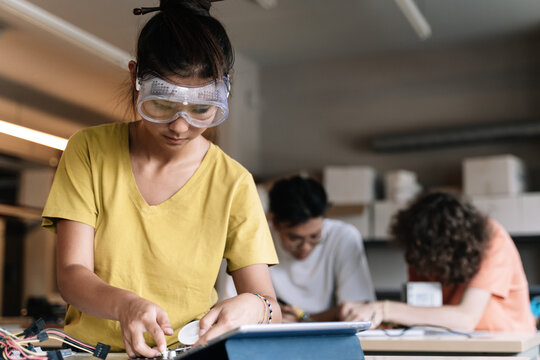 Asian Student Girl With Protective Goggles Learning Technology, Robotics And Electronics In High School