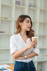 Asian businesswoman holding a cup of coffee in her office