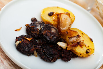 Traditional Spanish blood sausage slices with rice served with baked potatoes..