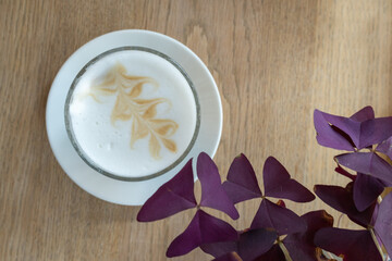 Top view of a latte macchiato with purple shamrocks (oxalis triangularis)